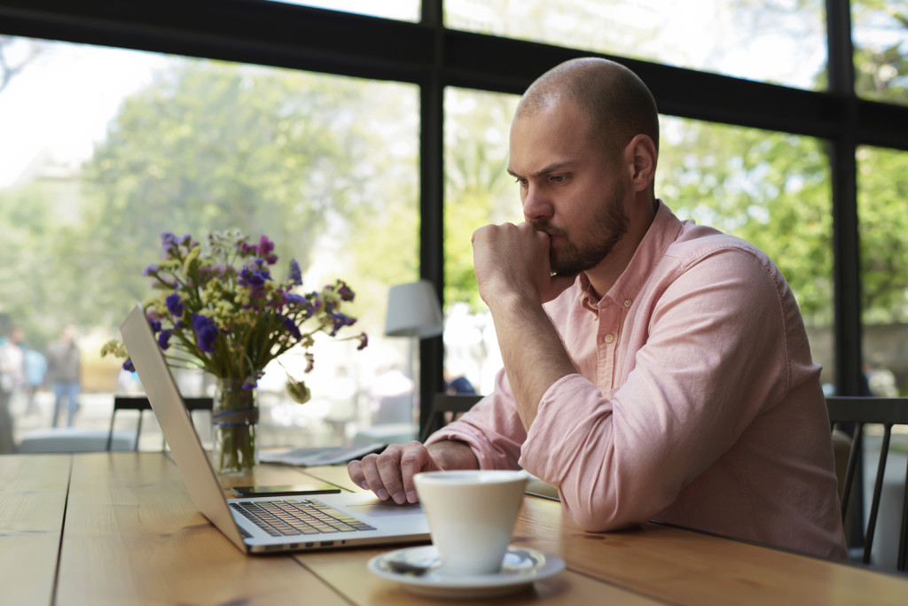 Thoughtful businessman work on notebook while sitting at wooden